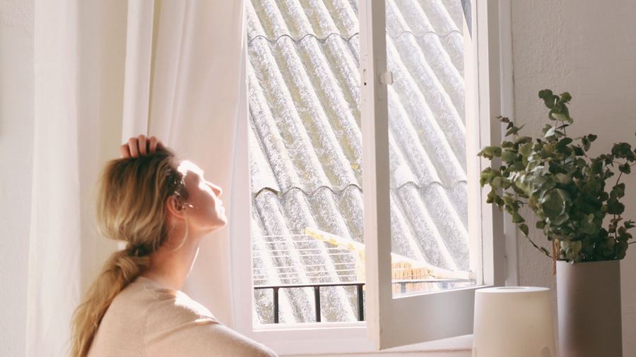 Person sitting by a window next to a desk